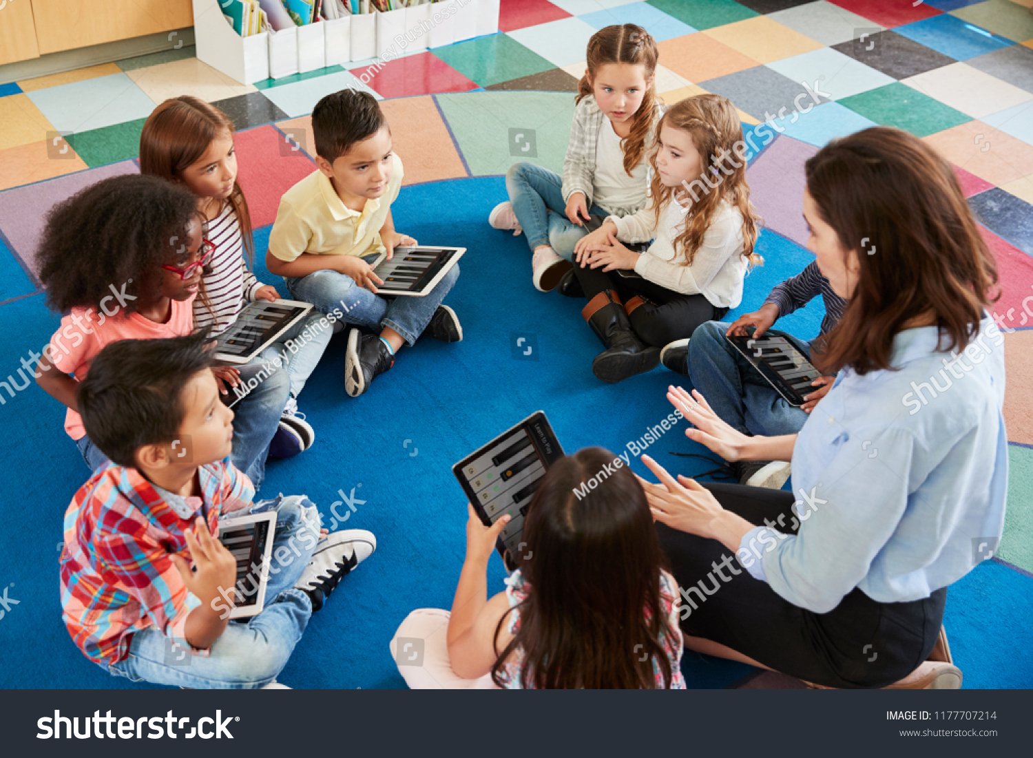 Lehrerin und Schulkinder arbeiten im Unterricht mit Tablets